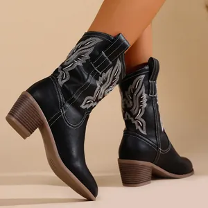 Vue détaillée de bottes de cowboy noires brodées avec des talons épais marron clair.