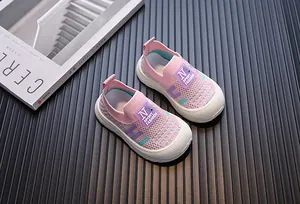 Detailed view of pink breathable knitted sneakers for children with soft white soles.
