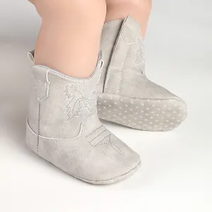 Détail de bottes de cowboy pour bébé en daim gris avec semelles souples antidérapantes.