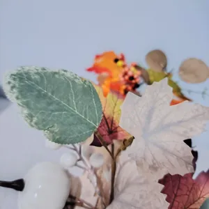 Close-up of autumnal artificial maple leaves and berries for harvest decor.