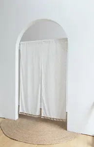 White Japanese noren door curtain with orange polka dots and tassel details in arched doorway
