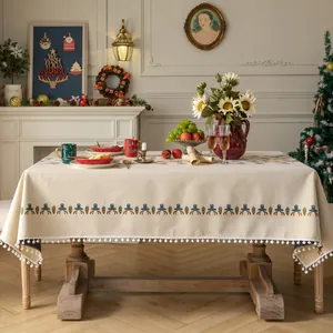 Tovaglia natalizia jacquard crema con pompon in una calda ambientazione da sala da pranzo.