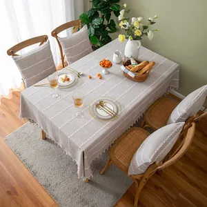 Detailed view of grey linen tablecloth with white stitching and fringe edges in dining room
