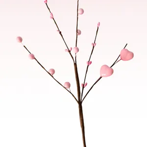 Close-up detail view of a pink artificial heart berry branch for festive home decor
