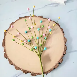 Detailed view of artificial colorful berry foam stems for home decor on wood slice.