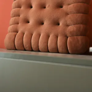 Detailed macro view of a soft brown biscuit-shaped plush cushion showing fabric texture
