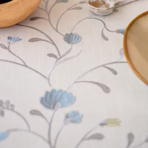 Close-up detail of elegant floral embroidery on a linen-textured tablecloth.