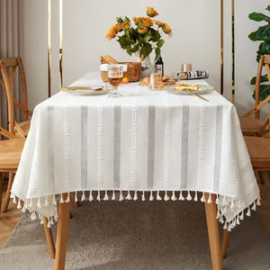 Close-up detail of white cotton linen tablecloth featuring hollow embroidery and tassel trim