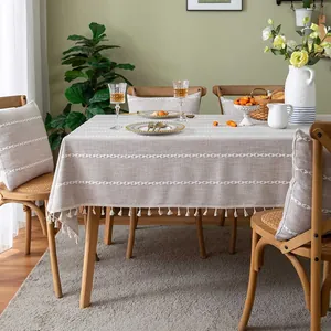 Detailed view of beige tablecloth with white geometric embroidery and fringe tassels