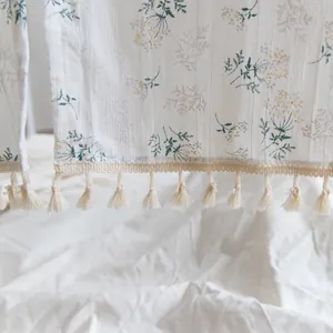 Close-up of floral cotton curtain detail with beige tassel fringe edge