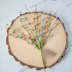 Close-up of colorful heart-shaped foam berry branches displayed on a rustic wood slice.