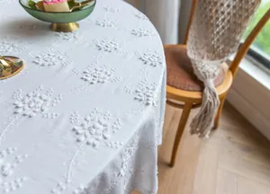 Gros plan d'une élégante nappe en dentelle brodée blanche avec des détails floraux français.