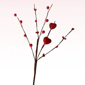 Detailed view of artificial branch with red glossy hearts and berries for holiday decor.
