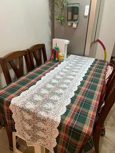 Elegante camino de mesa de encaje blanco con bordado floral sobre mantel de cuadros