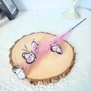 Detail view of artificial pink reed decoration with lifelike butterflies on wood slab