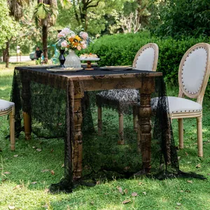 Elegant vintage black lace tablecloth draped on a wooden table in a lush garden