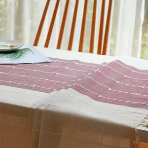 Detail eines bestickten Tischläufers mit Gittermuster und eleganten Quasten am Rand