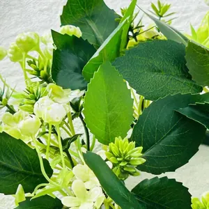 Detalle macro de una corona de hojas verdes artificiales con delicadas flores blancas pequeñas
