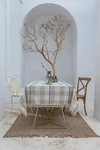 Detail der dunkelgrau-weiß karierten Tischdecke mit eleganten Quasten an den Rändern.