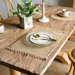 Rustic rectangular burlap placemats with elegant fringe shown on a wooden dining table
