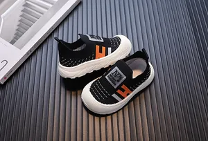 Close-up detail of children's fly-knit breathable slip-on sneakers in black and orange
