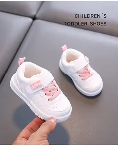 Detailed view of white children's toddler shoes with pink laces and velcro straps.