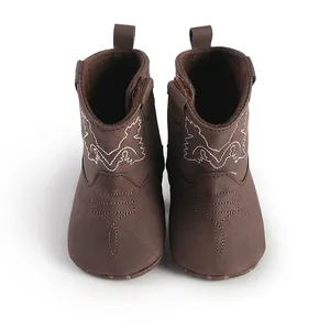Gros plan de bottes de cowboy marron pour bébé avec broderies blanches