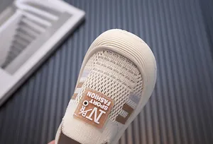 Close-up of breathable fly-knit texture and toe cap on cream children's sneakers.