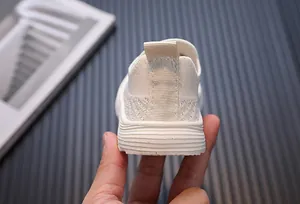 Detail view showing the breathable mesh texture and heel of cream kids sneakers