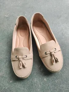 Detailed top view of beige women's loafers with elegant tassels and white stitching detail