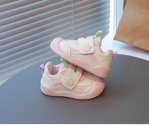 Primo piano di graziose scarpe da passeggio per neonati rosa e bianche con fragola e suola morbida