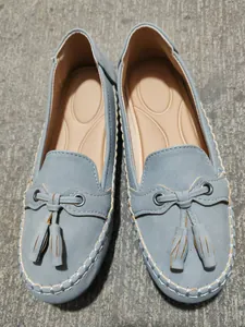 Top view of grey suede-like loafers with decorative tassels and soft soles