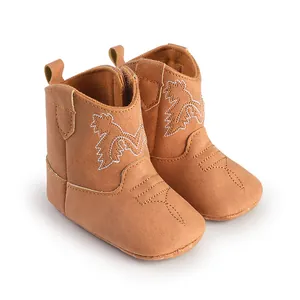 Gros plan détaillé de bottes de cowboy pour bébé marron à semelles souples brodées