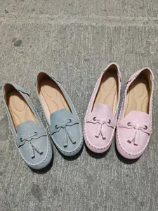 Detailed view of women's tassel loafers in light blue and pink on a textured surface
