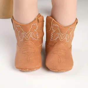 Bottes de cowboy beiges pour bébé avec broderie blanche et semelle souple pour les nouveau-nés.