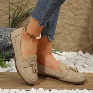 Close-up of stylish women's beige tassel loafers featuring stitched edges and soft soles