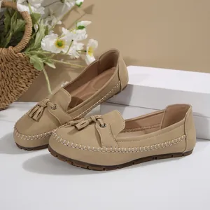 Macro detail of beige suede women's loafers featuring tassels and contrast stitching