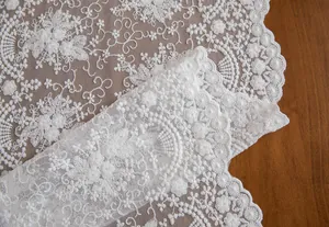 Vista detallada del encaje blanco bordado en 3D con bordes festoneados finos