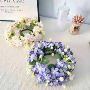 Detail view of pink and purple wildflower candle rings on a white cloth