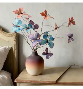 Detailaufnahme eines 3D-Schmetterling-Blumenarrangements in einer Vase auf dem Nachttisch.