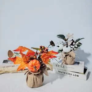 Pair of harvest-themed artificial pumpkin and maple leaf arrangements in burlap bases.