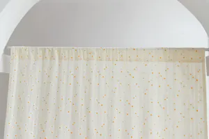 Detailed view of a minimalist cream cotton door curtain featuring small yellow floral patterns