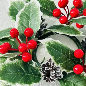 Primer plano detallado de una corona de Navidad con bayas rojas y piñas naturales.
