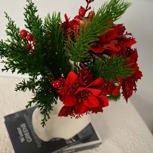 Close-up of vibrant artificial Christmas flowers with red poinsettias in a white vase