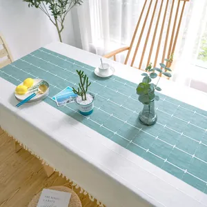 Detail einer weiß-türkisen Tischdecke mit Gittermuster und eleganten Quasten am Rand.