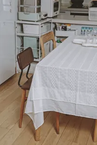 Detailed texture of white French lace embroidered tablecloth in a cozy dining room