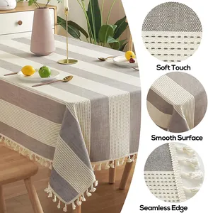 Gros plan d'une nappe en coton et lin à rayures grises et blanches avec glands élégants.