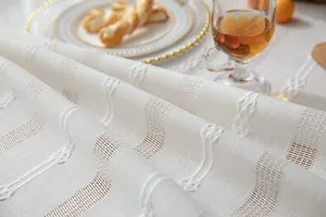 Detail view of white rustic linen tablecloth with delicate embroidery and openwork.