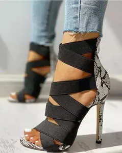 Close-up of sexy Roman-style high-heeled sandals with black elastic straps and snake print detail.