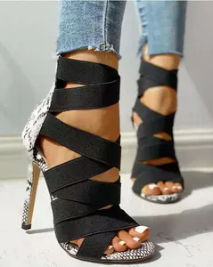 Close-up of sexy Roman high-heeled sandals with black elastic straps and snakeskin detail